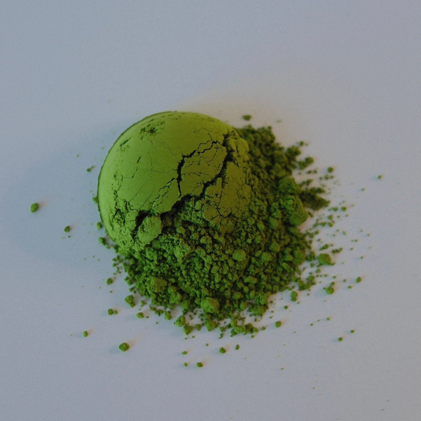 Green powder with a small ball of green powder on a white background